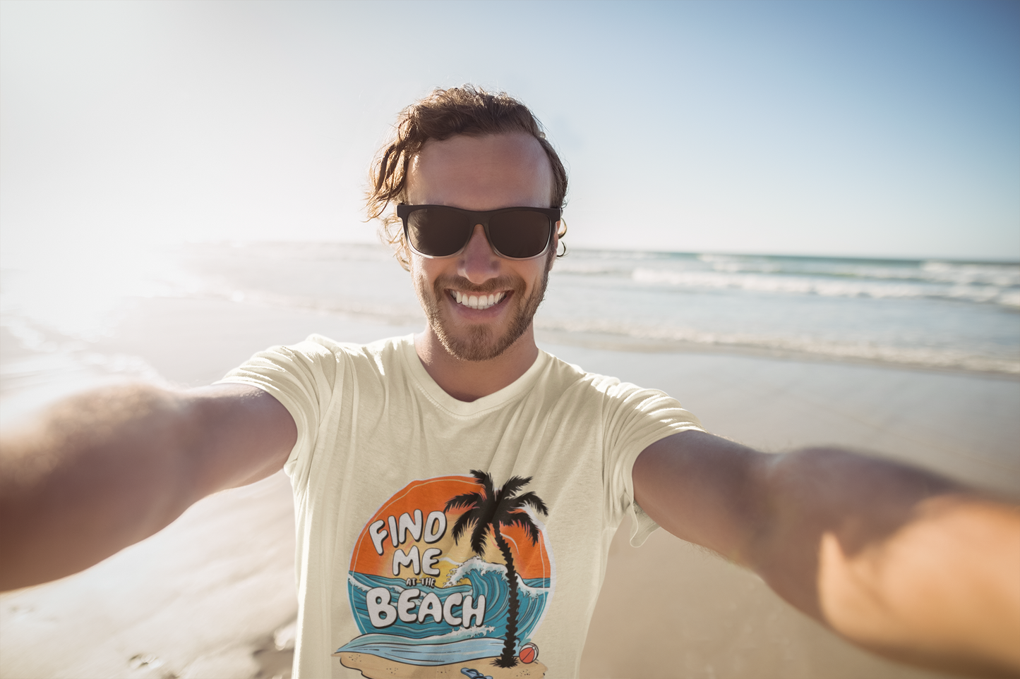 Smiling man taking a selfie at the beach in the Find Me at the Beach t-shirt