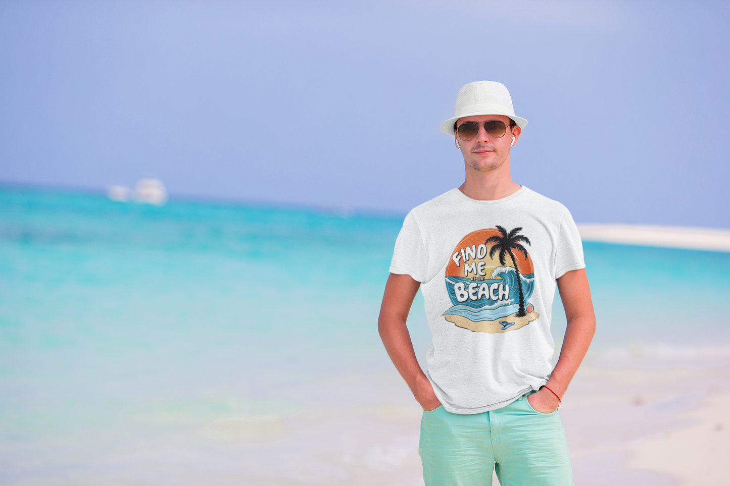 Stylish man in sunglasses and a hat wearing the Find Me at the Beach t-shirt on a bright tropical beach