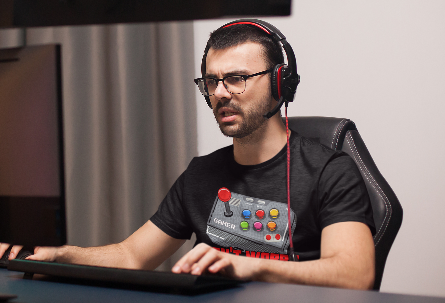 Gamer in black "Just One More Game" T-shirt wearing headset with frustrated expression