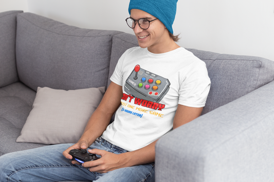 Young man wearing the white "Just One More Game" tee while gaming on a couch