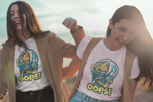 Two women laughing together at the beach while wearing matching “Oops!” graphic tees, showcasing the fun and playful design